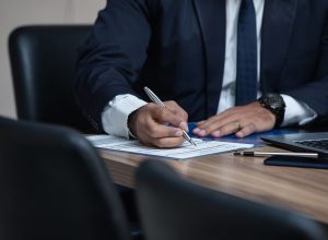 man in business suit signing papers on wooden table